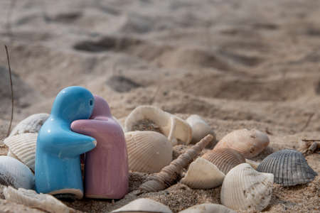 Ceramic couple dolls and shells in sand on the beach and copy space. Concept for anniversary, Wedding and eternal love concept, Romance wedding or Valentineâs day. Selective focus.の写真素材