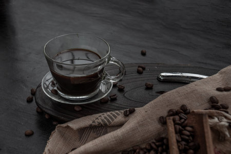 Coffee style, Cup of coffee and coffee beans roating with old wooden scoop and coffee beans around...