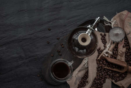 Coffee style, Cup of coffee and coffee beans roating with old wooden scoop and coffee beans around on the wooden and dark stone background. Top view with copy space for your text.の写真素材