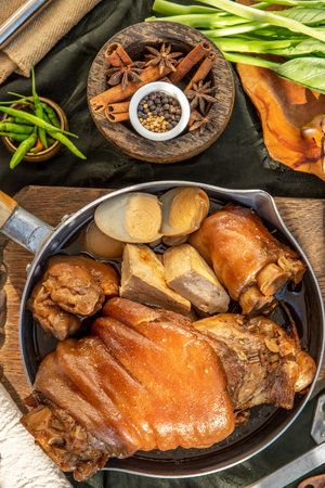 traditional dish Stewed pork leg with boiling sweet gravy sauce and boiled egg, tofu, kale Served with Pickled Lettuce and pickled chilli on black background. Selective focus.の写真素材