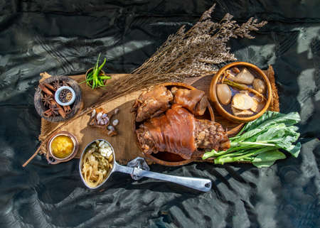 traditional dish Stewed pork leg with boiling sweet gravy sauce and boiled egg, tofu, kale Served with Pickled Lettuce and pickled chilli on black background. Selective focus.の写真素材