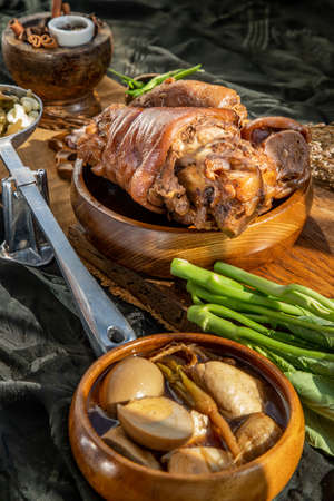 traditional dish Stewed pork leg with boiling sweet gravy sauce and boiled egg, tofu, kale Served with Pickled Lettuce and pickled chilli on black background. Selective focus.の写真素材