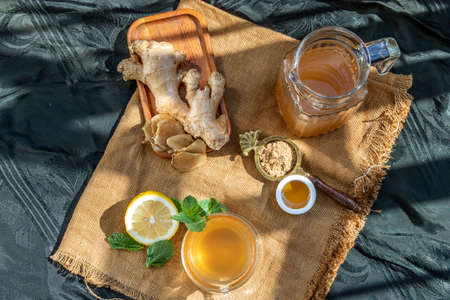 Hot Ginger juice with lemon and mint, root and slices of ginger Served with brown sugar and honey on sackcloth background. Hot ginger juice can helps warming body, Healthy Drink.の写真素材