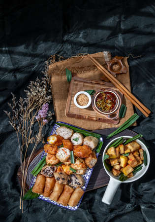 Many vegetarian food : Fried taro rolls (Taro Guangjian) and Deep fried spring rolls, Fried tofu, Fried radish, Fried taro and black beans (Zhu jiao quan or Fried taro cakes) Served with spicy sweet sauce and roasted crushed peanuts with wooden chopsticks on Ceramic dishes. Selective focus.の写真素材