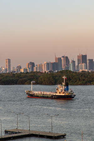 Bangkok, Thailand - 26 Mar 2020 : Two cargo ship parked in the middle of the river and in front of a green tree by the Chao Phraya River.のeditorial素材