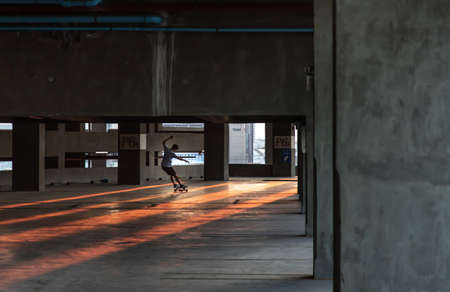 Bangkok, thailand - Mar 26, 2020 : A young man riding a skateboard in a parking lot at evening. The concept of modernity, youth and active lifestyle. No focus, specifically.のeditorial素材