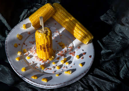 Grilled corn on the cob  on classic white plate over dark background. Ideas for barbecue and grill parties, Barbecue concept.の写真素材