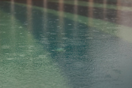 Rain drops falling in the swimming pool. Water surface for background and abstract.