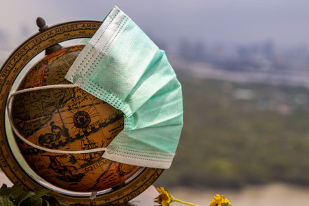 Bangkok, Thailand - Jun 25, 2020 : The globe is wearing a disposable medical mask. Concept of prevent spread of corona virus covid-19. Everyone should wear mask in public. Coronavirus pandemic, World quarantine, Selective focus. Copy space.のeditorial素材