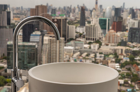 Modern hygienic hand basin with cityscape that can look outside from big window. Elegant faucets and...
