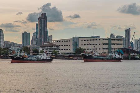 Bangkok, Thailand - 10 Jul 2020 : Two cargo ship parked in the middle of the Chao Phraya River with city at the background.のeditorial素材