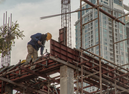 Construction Worker Welding soldering metal girders and Sparks in a Structure high above at the...