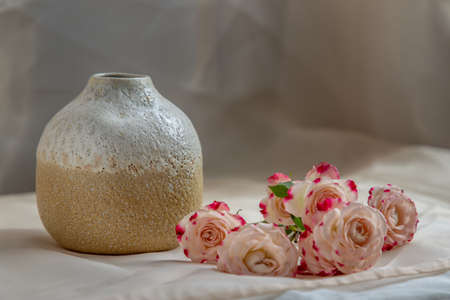 Blue handmade ceramic vase with Pink flower on Blush textured table cloth. Home decor, Copy space, Selective focus.の写真素材