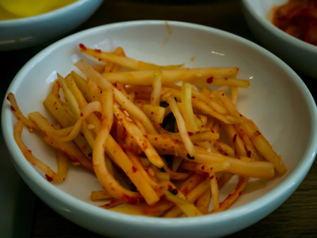 Hand using chopsticks pick Korean seasoned beansprout (Mild kongnamul muchim) in a white cup for eating. Asian side dish Pickled radish, Korean food traditional. No focus, specifically.の写真素材