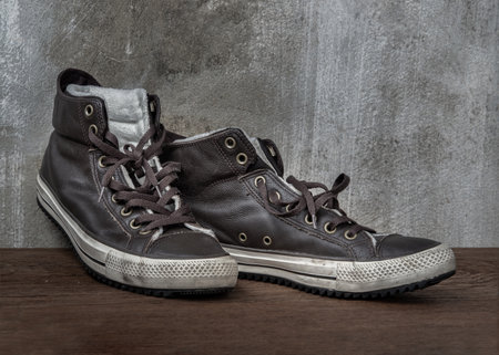 Brown Retro High Top Canvas Sneakers was placed on old wooden floor. Vintage age-worn sneakers canvas shoes brown, Concept : Sometimes the long journey of life should rest. Copy space, Selective focus.の写真素材