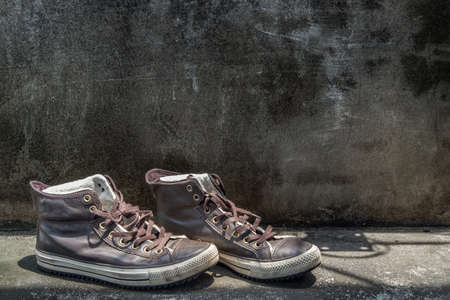 Brown Retro High Top Canvas Sneakers was placed on old cement floor. Vintage age-worn sneakers canvas shoes brown, Concept : Sometimes the long journey of life should rest. Copy space, Selective focus.の写真素材