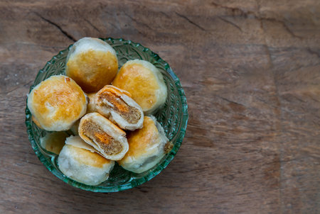 A traditional asian pastry or Tao Sor on rustic wooden table. Chinese sweet pastry filled with mung...