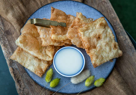 Homemade Sweet Crispy Thai Roti (Thai Pancake) Served with Sweetened condensed milk on ceramic plate. Delicious Thai Dessert, Selective focus.の写真素材