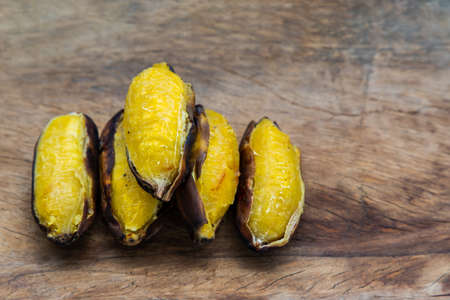 Grilled silver bluggoe banana or Kluai hak mook on old wooden background. Delicious golden brown grilled banana, Ancient food recipes. Copy space, Selective focus.の写真素材