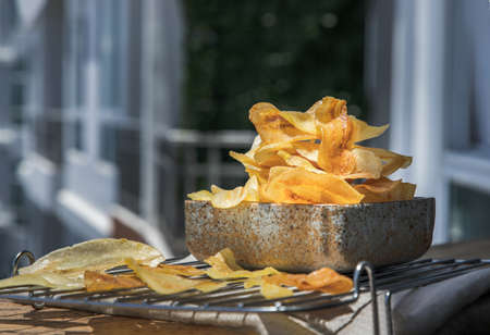 Close-up of Homemade banana chips in wooden bowl and glass jar on wooden background. Banana dessert, Long banana chips, Selective focus.の写真素材