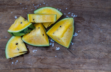 Fresh juicy yellow watermelon cut into triangles on old wooden table at balcony with city view. Tropical fruits, Select focus.の写真素材