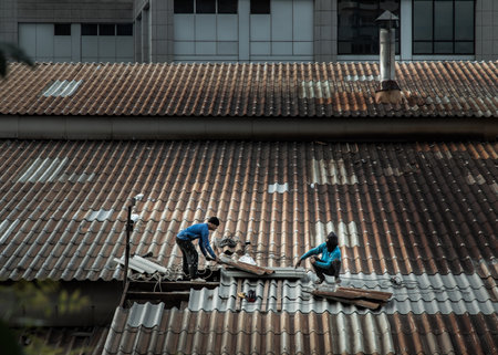 Bangkok, Thailand - 28 May 2021 : Two handyman workers repairing tiles on the damaged factory roof. Selective focus.のeditorial素材