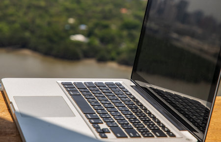 Glass crystal blue apple on laptop keyboard on a wooden table at balcony and nature view. Selective...