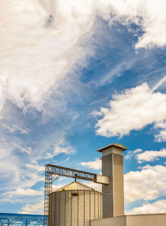 The complex agricultural silo installations for the storage of grain on blue sky background. Grain processing complex intended for coarse purification, drying up, Copy space, Selective focus.の写真素材