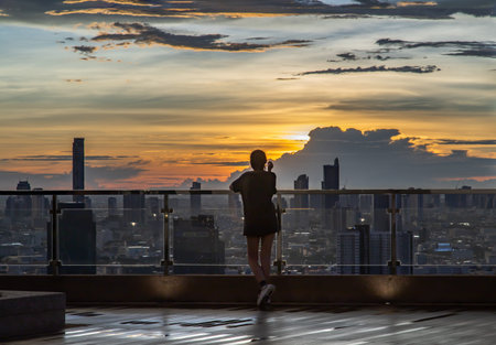 Bangkok, Thailand - 02 Jul 2021 : A young woman relaxing on rooftop terrace with overlooking the...