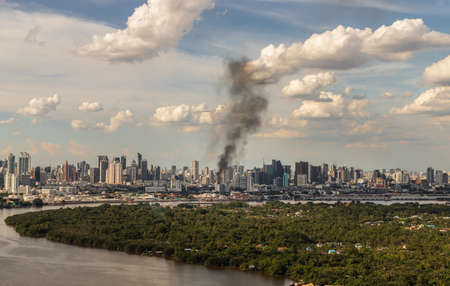 Bangkok, Thailand - 04 Jul, 2021 : Plume of smoke clouds from burnt building on fire at some area in the city. Fire disaster accident, Selective focus.のeditorial素材