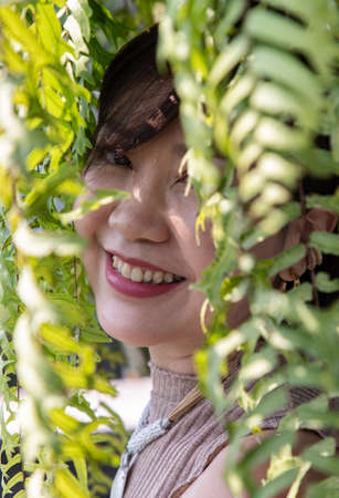 A young asian woman sitting and relax on cushion on rattan sofa  near glass window in living room. Selective focus.の写真素材