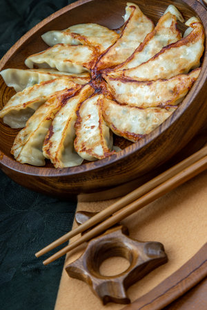 Fried japanese gyoza dumplings on wooden bowl served with soy sauce and chopsticks. Asian dinner, Selective focus.の写真素材