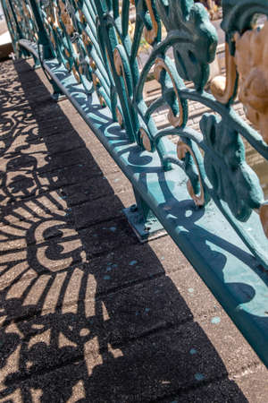 Wrought iron decorative fence on bridge. Forming an interesting design with it's cast shadow on the floor. Selective focus.の写真素材