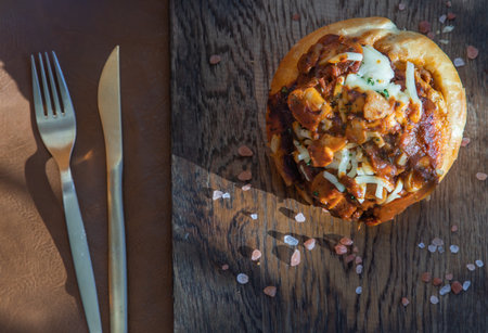 Homemade pizza buns topped with tomato sauce, ham, sausage, green onion and mozzarella cheese with...