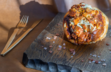 Homemade pizza buns topped with tomato sauce, ham, sausage, green onion and mozzarella cheese with himalayan pink salt on rustic wooden board.の写真素材
