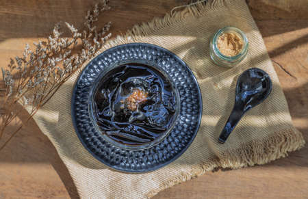 Black grass jelly (Mesona chinensis) Dessert herbal gelatin or jelly black with ice and brown sugar on the wooden background. Sweet delicious dessert chinese style.の写真素材