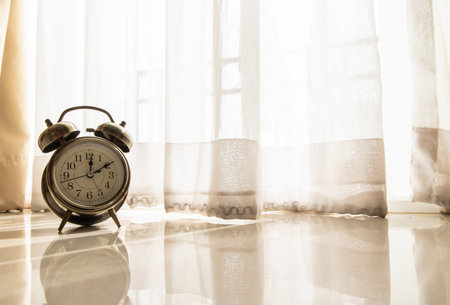 Alarm clock in the room that have early light through the beautiful curtain for background. Concept...