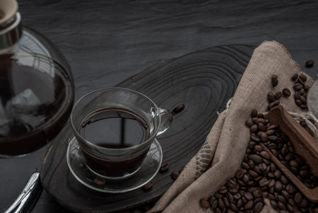 Coffee style, Cup of coffee and coffee beans roating with old wooden scoop and coffee beans around...