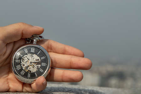 A retro pocket watch with chain in the palm of the girl's hand. Sky background. Copy space.の写真素材