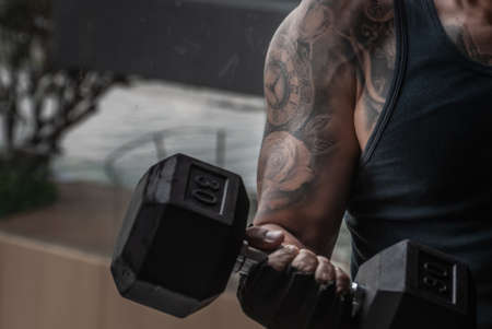 Bangkok, Thailand 06 Oct 2019 : Closeup of Strong bodybuilder, power athletic man in training pumping up muscles with dumbbell in gym or fitness club.のeditorial素材