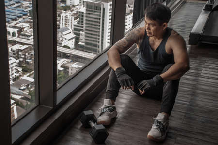 Bangkok, Thailand 06 Oct 2019 : Sport man sitting and resting after workout or exercise in fitness gym. Relax concept. Strength training and Body build up theme.のeditorial素材