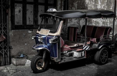 Bangkok, Thailand - Dec 7, 2019 : Famous blue Tuk Tuk, Thai traditional taxi with an old ancient wall behind.のeditorial素材