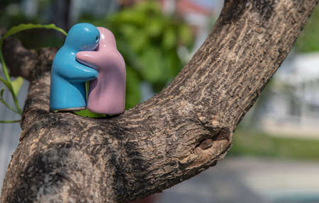 Blue and pink ceramic couple dolls hug with each other on the tree. Concept for anniversary, Wedding and eternal love concept, Romance wedding or Valentineâs day.の写真素材