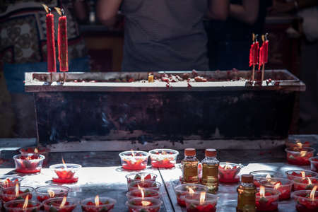 Bangkok, Thailand - 27 Oct 2019 : Burning red flower candle at chinese shrine for making merit. Lighting incense and candles for worship Buddha.のeditorial素材
