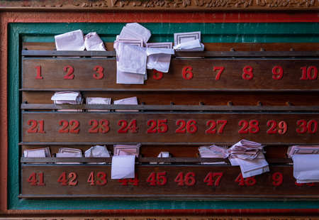 Chinese fortune telling paper strips in wooden shelves a row along with red numbers at Chinese shrine. No focus, specifically.の写真素材