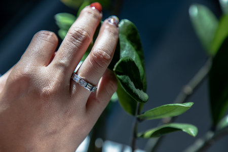 Women hand. Sterling silver female ring on the fingers of a lady and red nail on nature background....