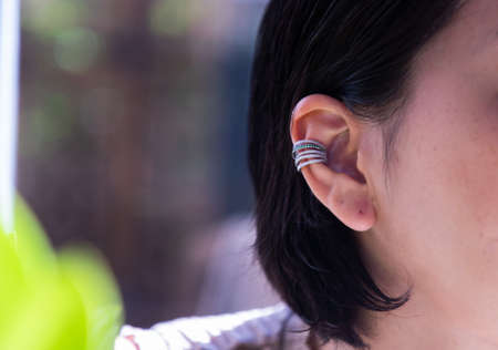 Detail of young woman wearing beautiful silver earring. Women accessories. Selective focus.の写真素材