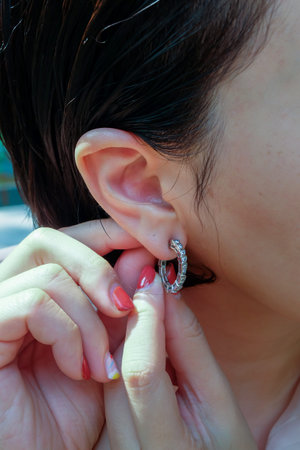 Detail of young woman wearing beautiful silver earring. Women accessories. Selective focus.の写真素材
