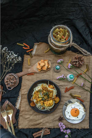 Spaghetti topped with Stir fried spicy snapper on a brown plate Served with Fried Egg and Crispy butter toast. Top view, No focus, specifically.の写真素材