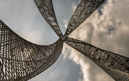 Bangkok, Thailand - 20 May 2021 : Golden steel sculpture for decorative attractive at park. Architectural structure consists of decorative metallic, Photographed from a low angle against a blue sky in the background. Selective focus.のeditorial素材